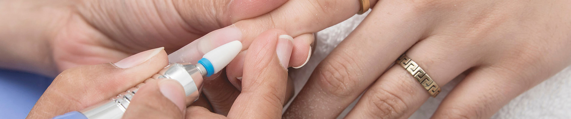 A student using an e-file on a client's nails.