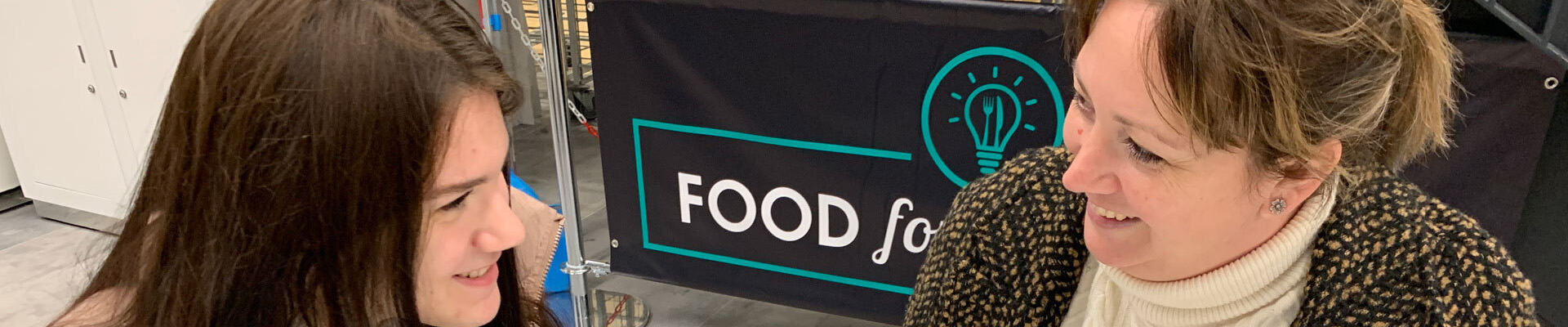 A member of and staff and a student talking in the canteen at the City Hub.