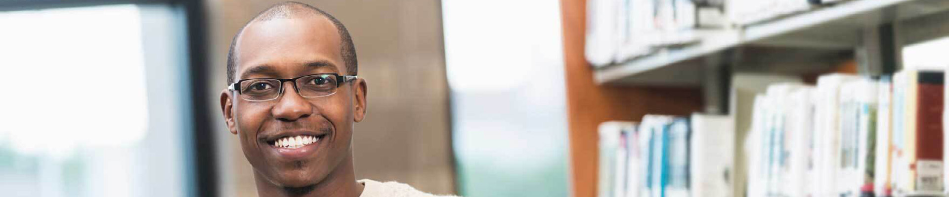 A man wearing glasses smiling in a library.