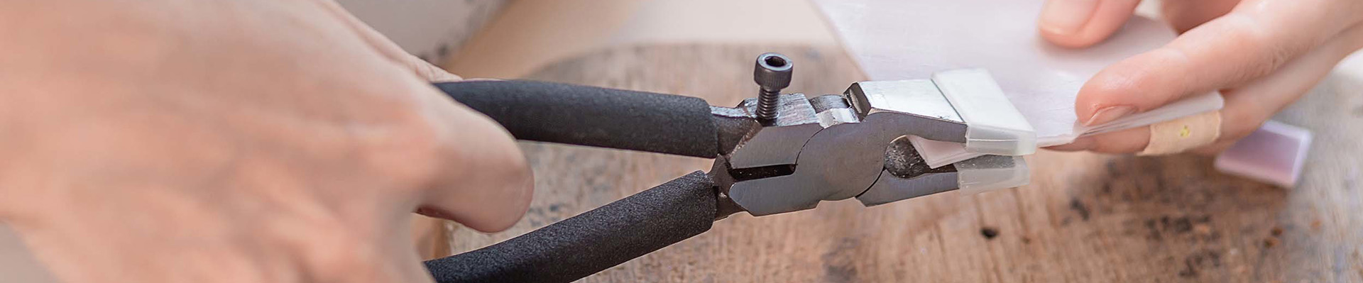 A person cutting glass with glass clippers.