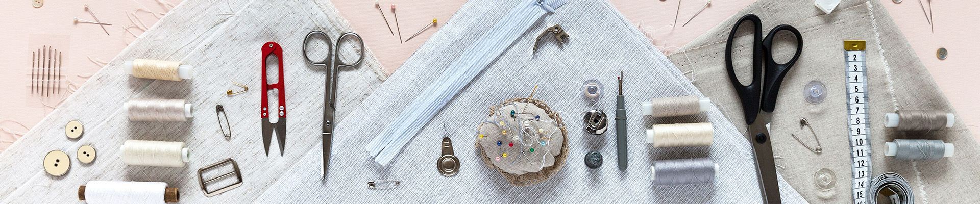 A collection of sewing accessories including thread, scissors, a tape measure, buttons and pins.