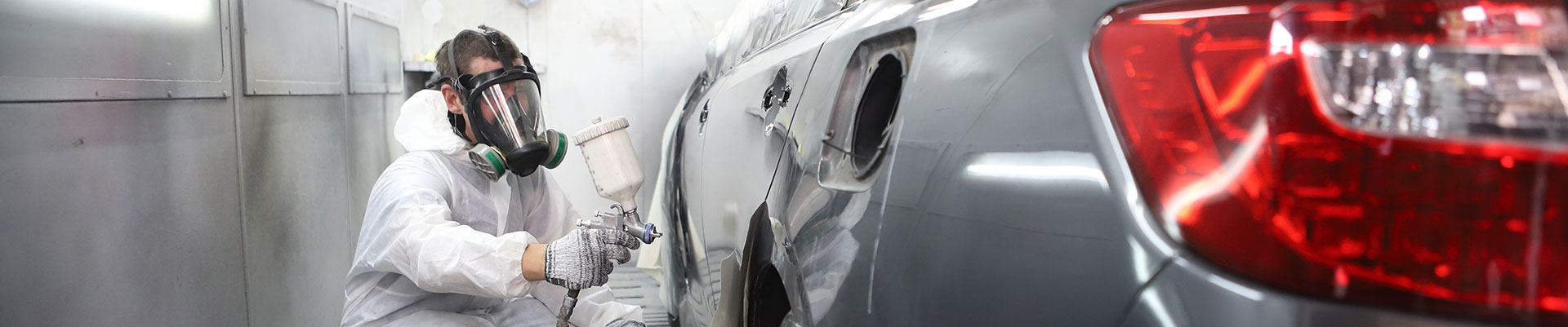 A paint technician spraying the side of a car