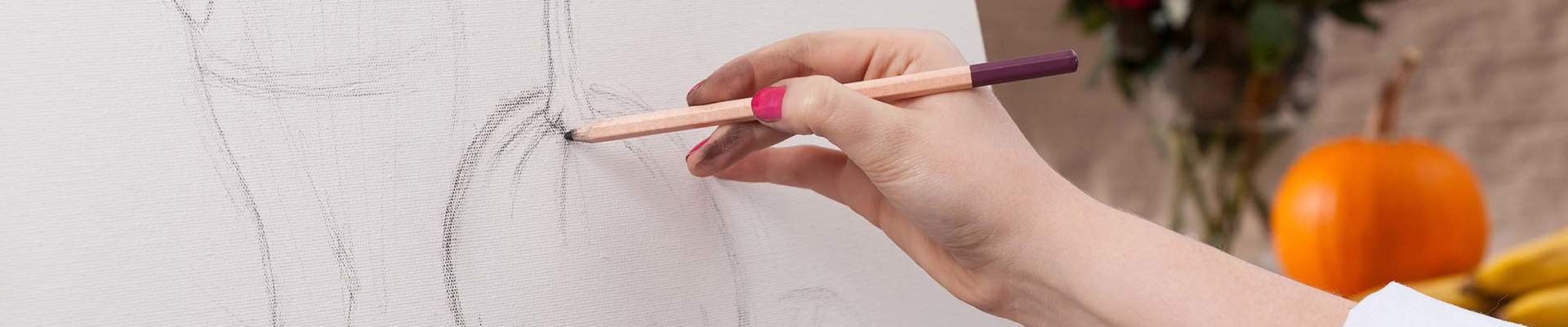 A student painting a pumpkin and a vase of flowers