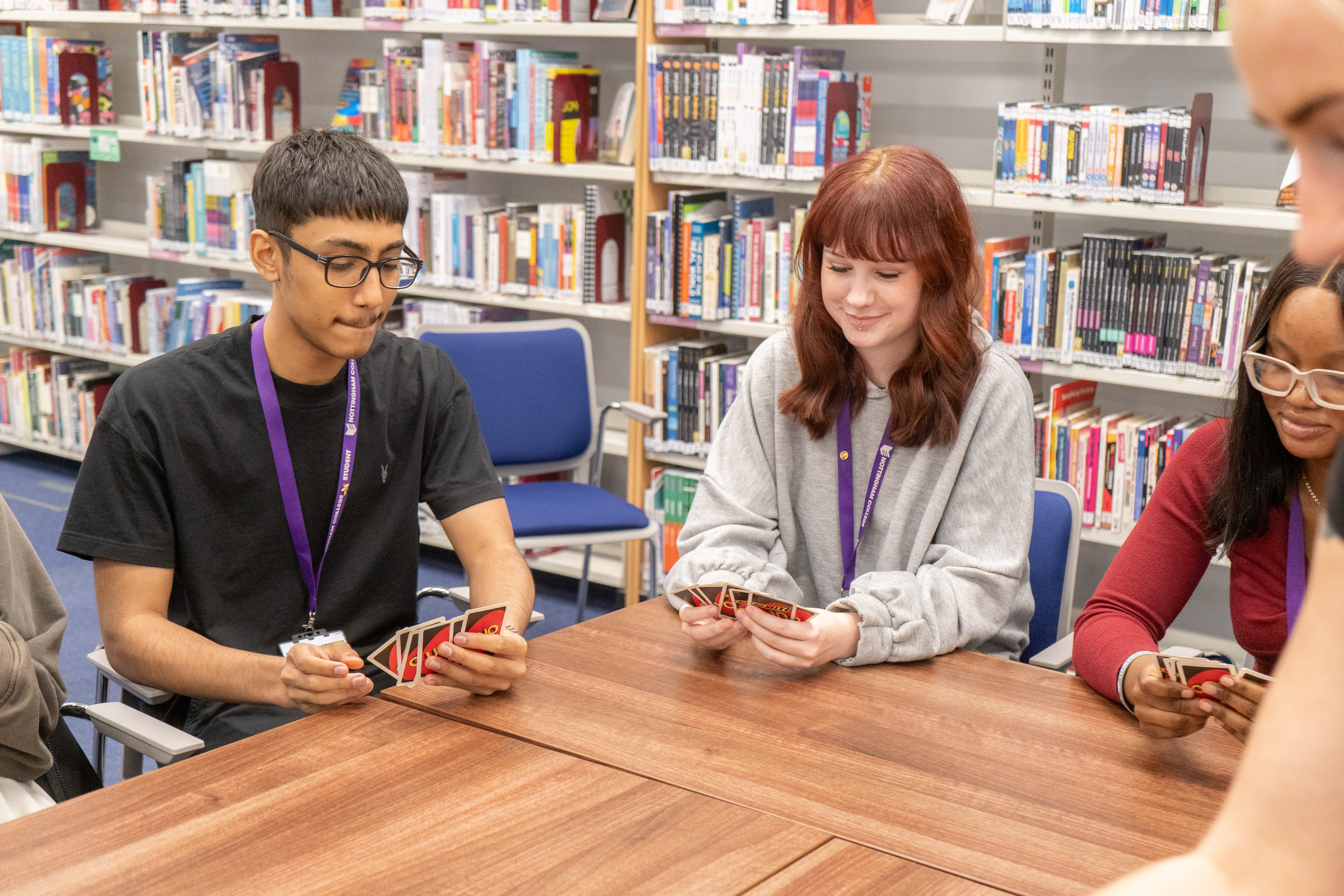 A group of students playing a card game in the library