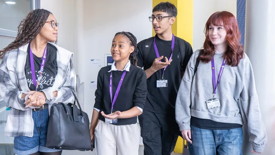4 students smiling walking down a corridor