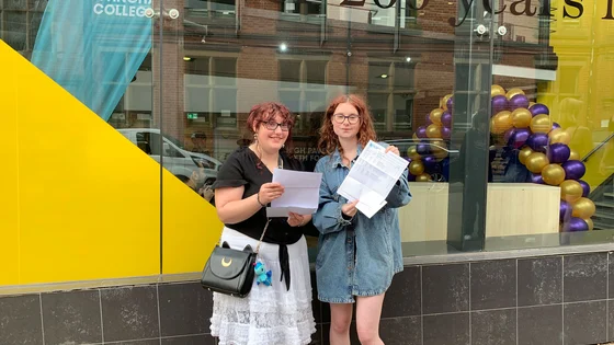 Two A level students smiling holding their exam results