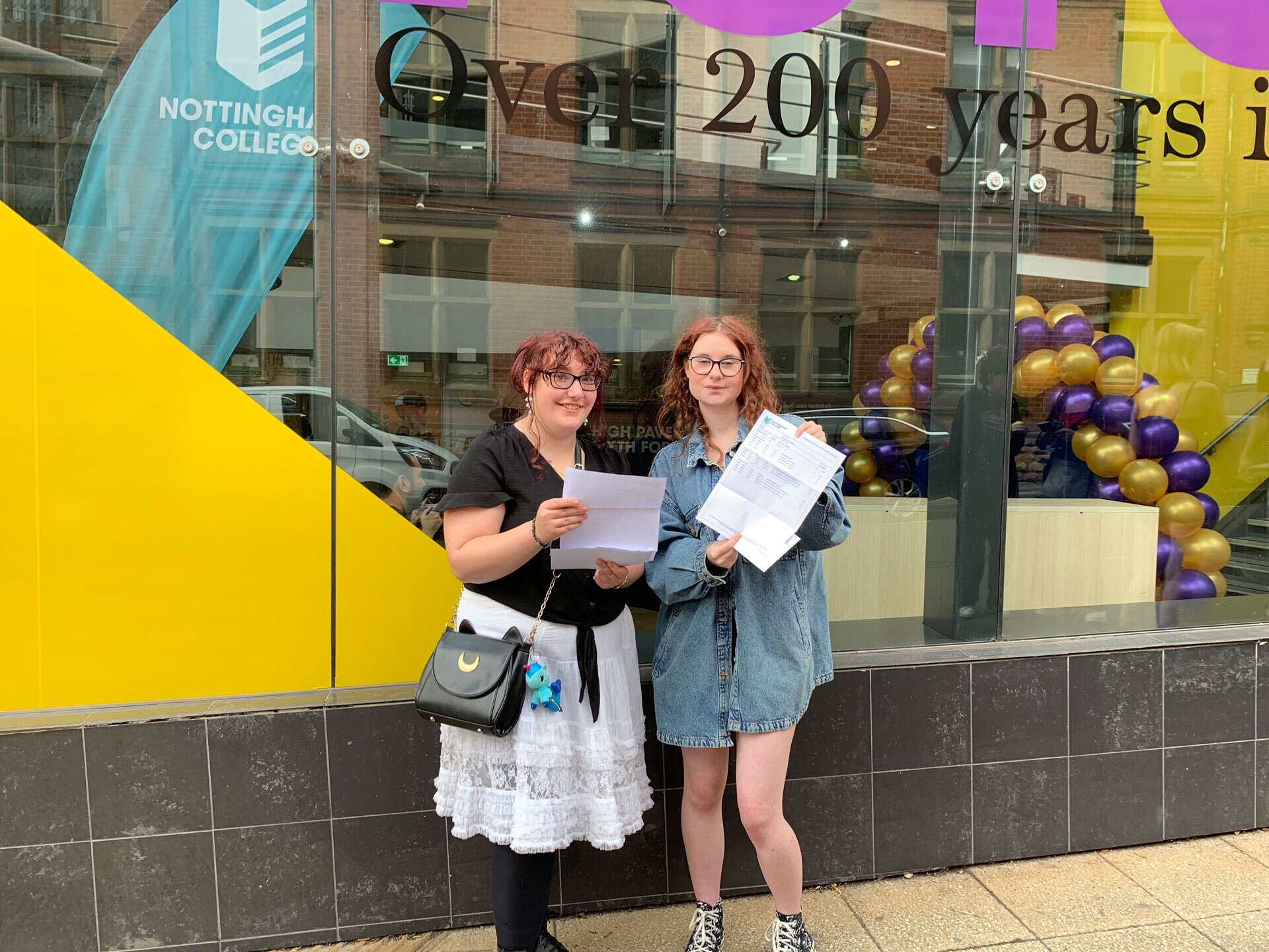 Two A level students smiling holding their exam results