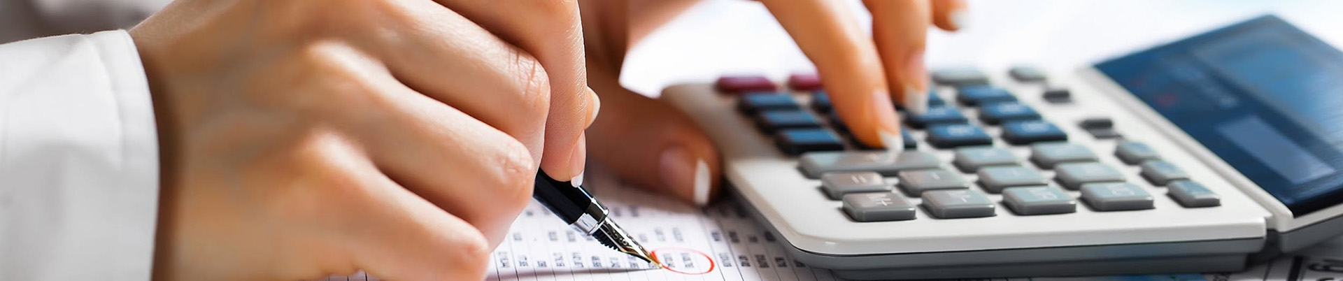 A student writing on a financial statement and using calculator.