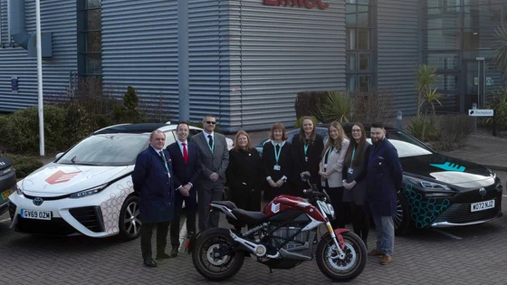 Staff outside the Emtec building with hydrogen cars and an electric bike.