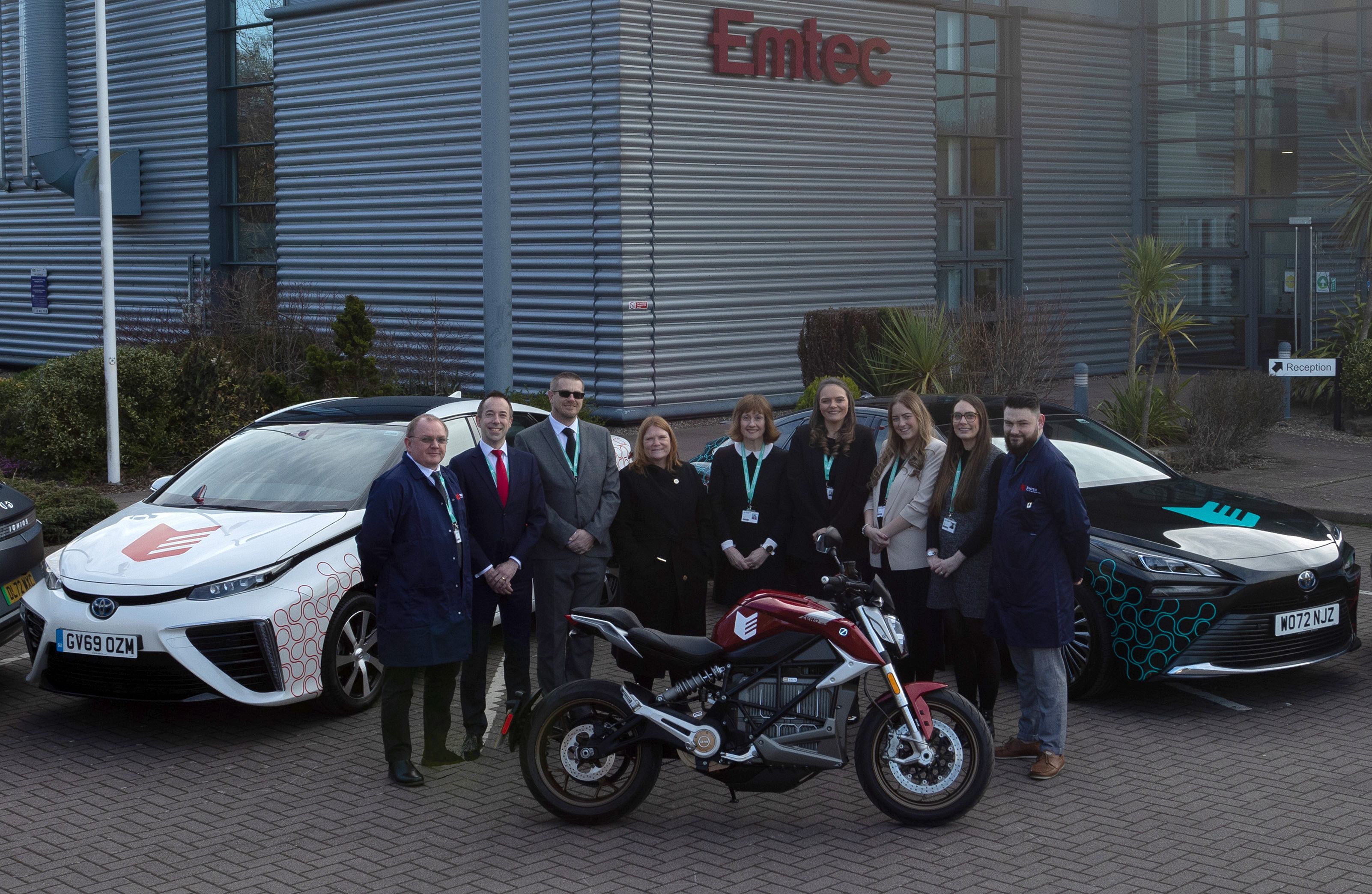 Staff outside the Emtec building with hydrogen cars and an electric bike.
