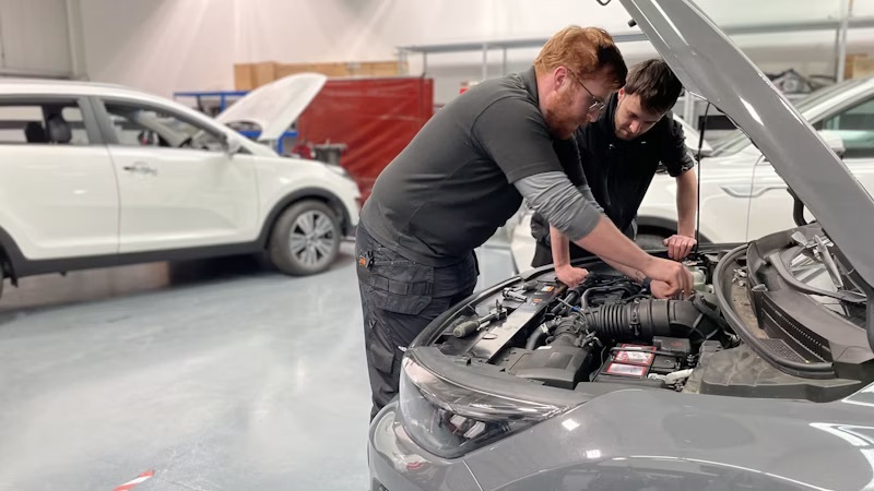 Students working on the engine of a car in an automotive workshop at Emtec in Ruddington.