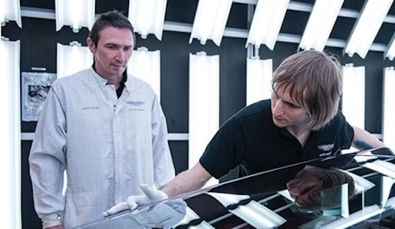 An assessor inspecting the work of a bodywork repair apprenticeship in a workshop