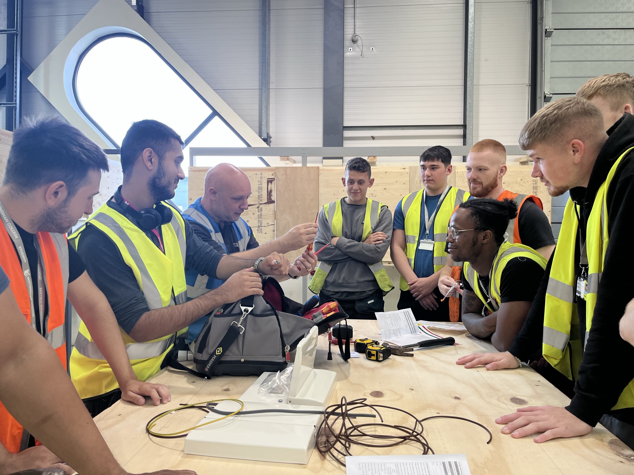 Construction apprentices gather round a workbench listening to their tutor