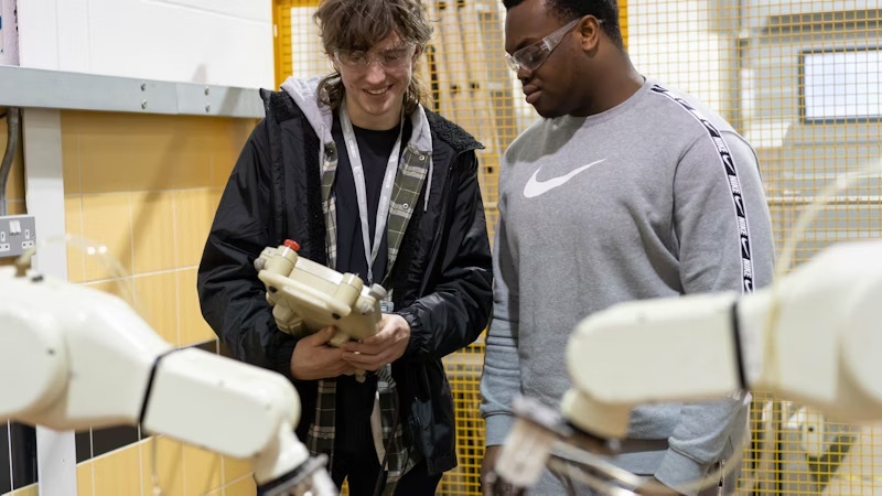 Students operating machine robots in an engineering workshop at Highfields.