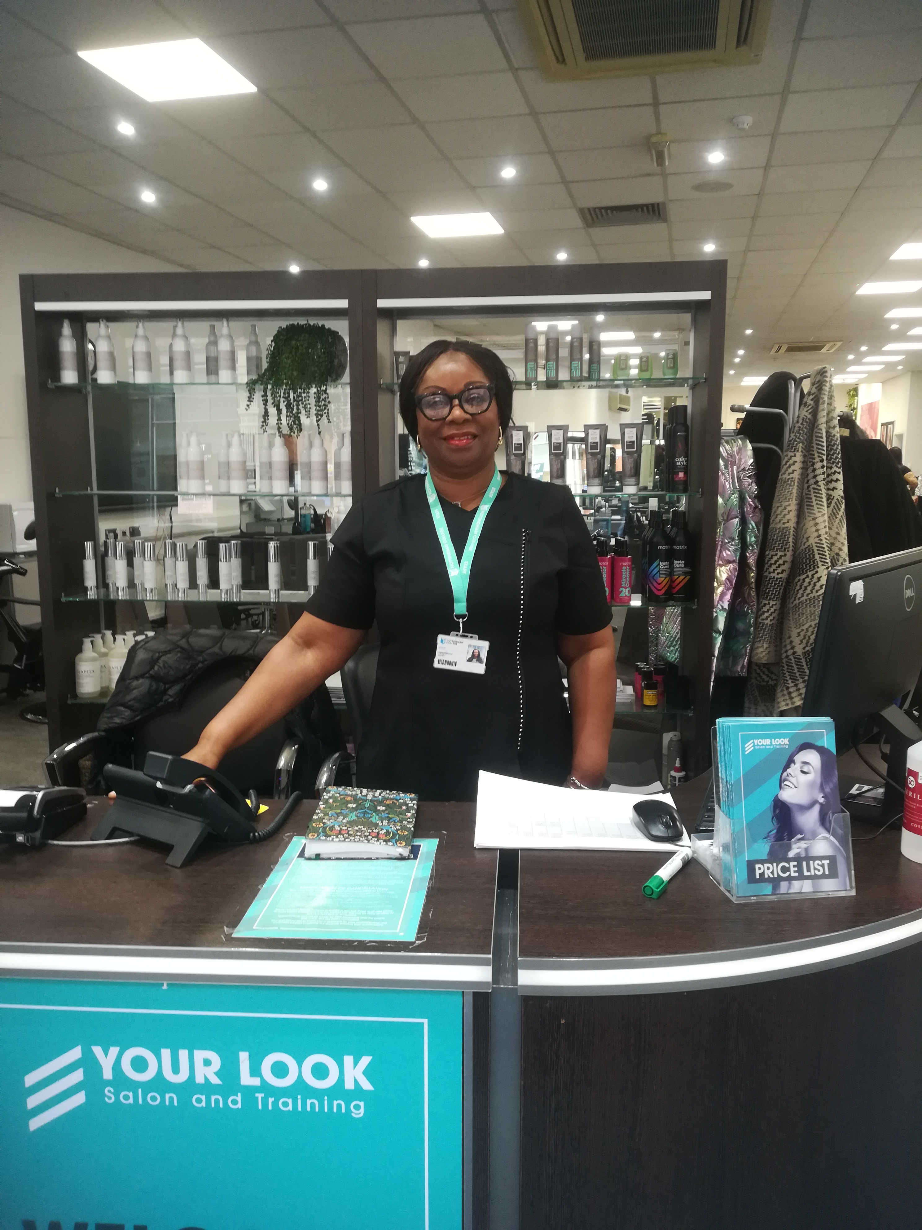 Sally stood behind the reception desk smiling at the camera
