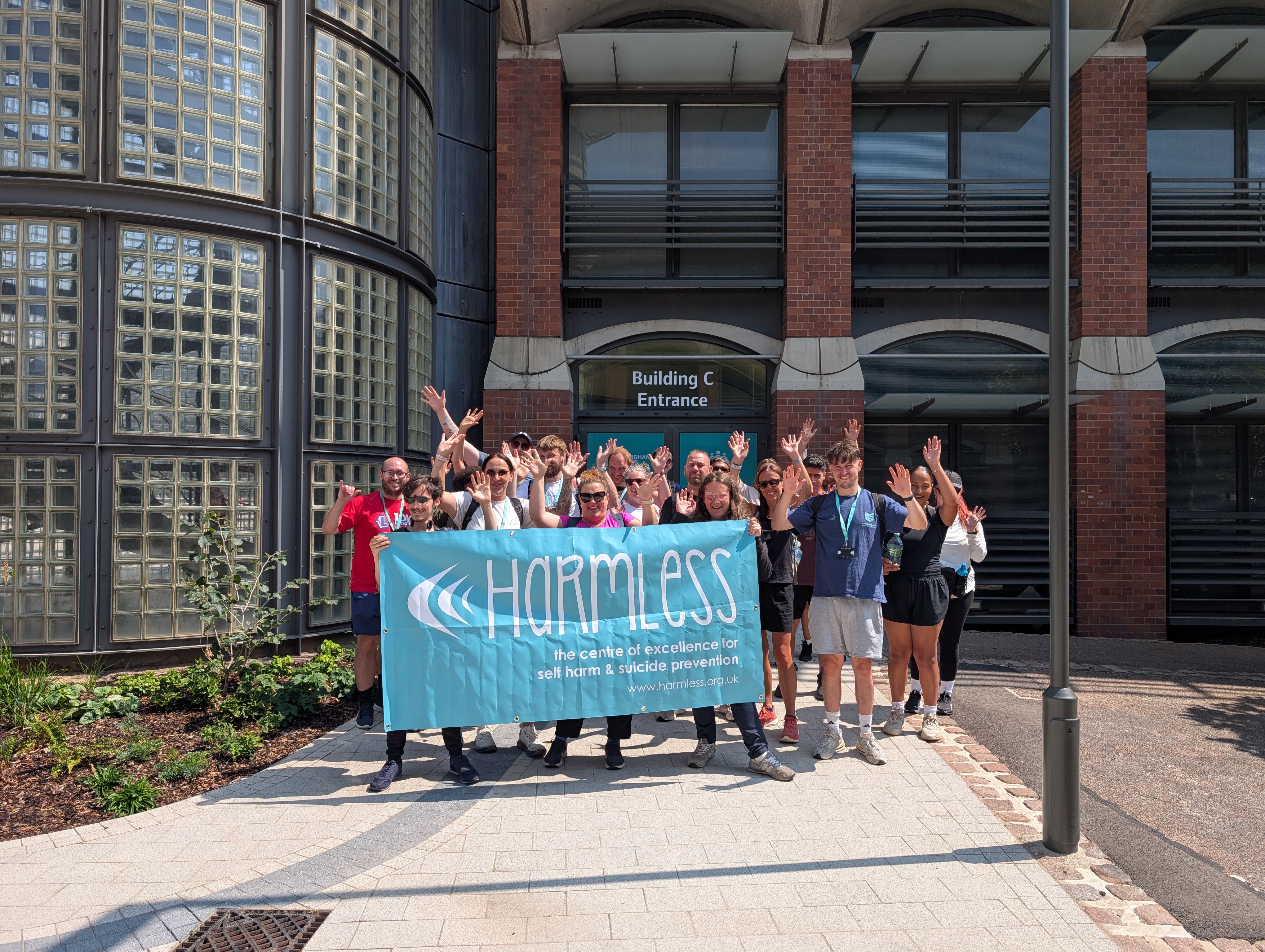 Staff and students outside Castle Meadow holding a banner that has the charity Harmless text written on it