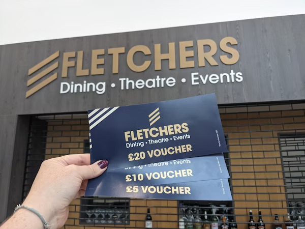 A person holding a selection of Fletchers gift vouchers.