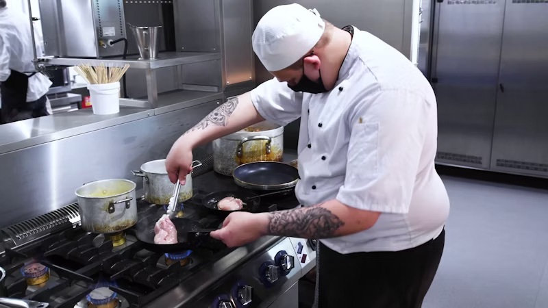 A student preparing food in the training kitchen at the City Hub.