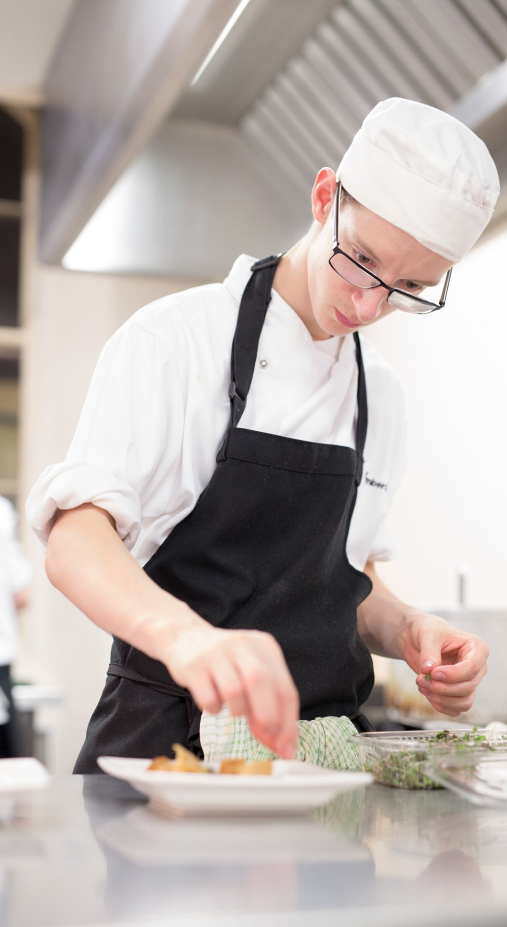 A catering student preparing some food in the kitchen