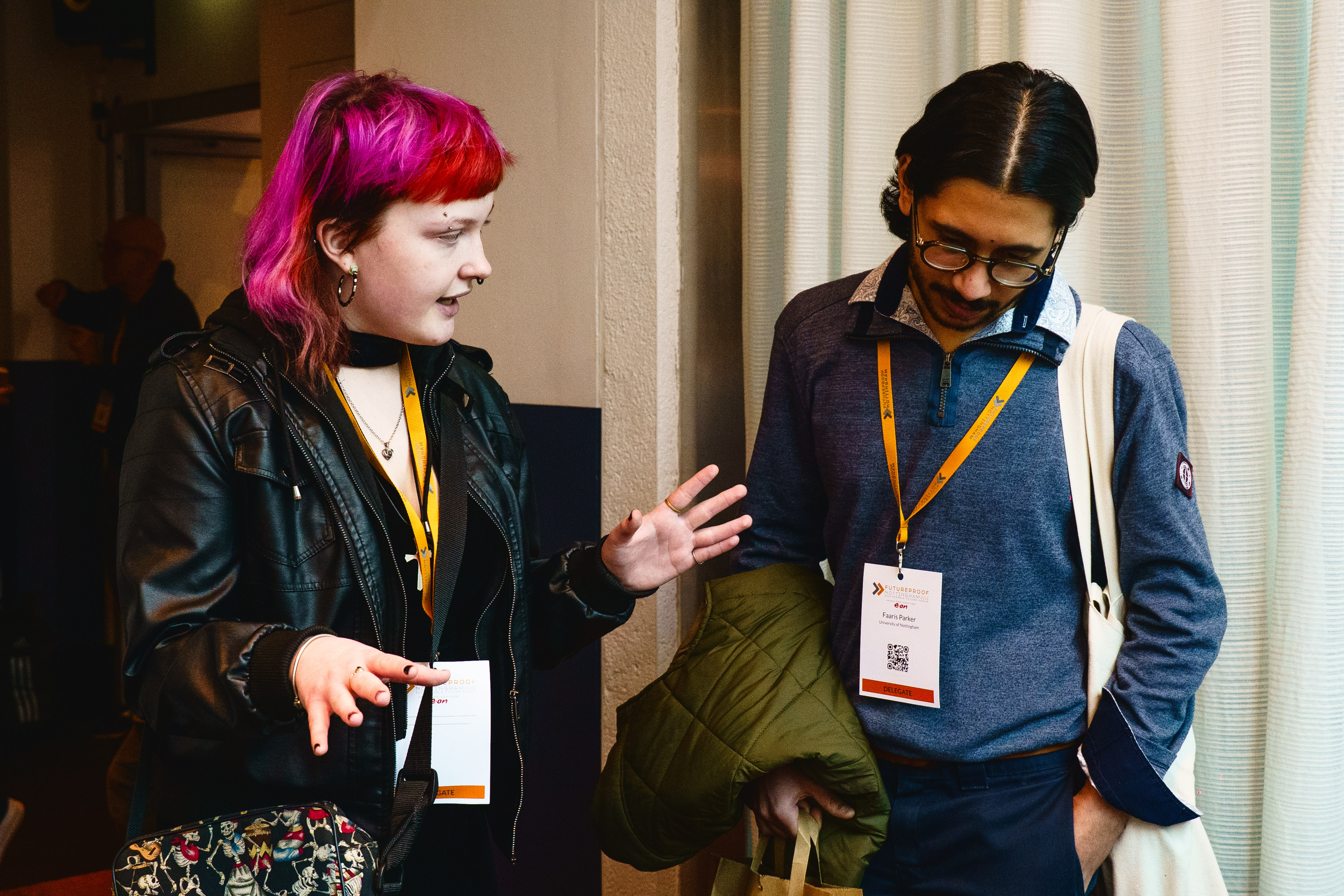 A pink haired student named Jazz talks to another person attending the FUTUREPROOF event wearing a blue long sleeve shirt.