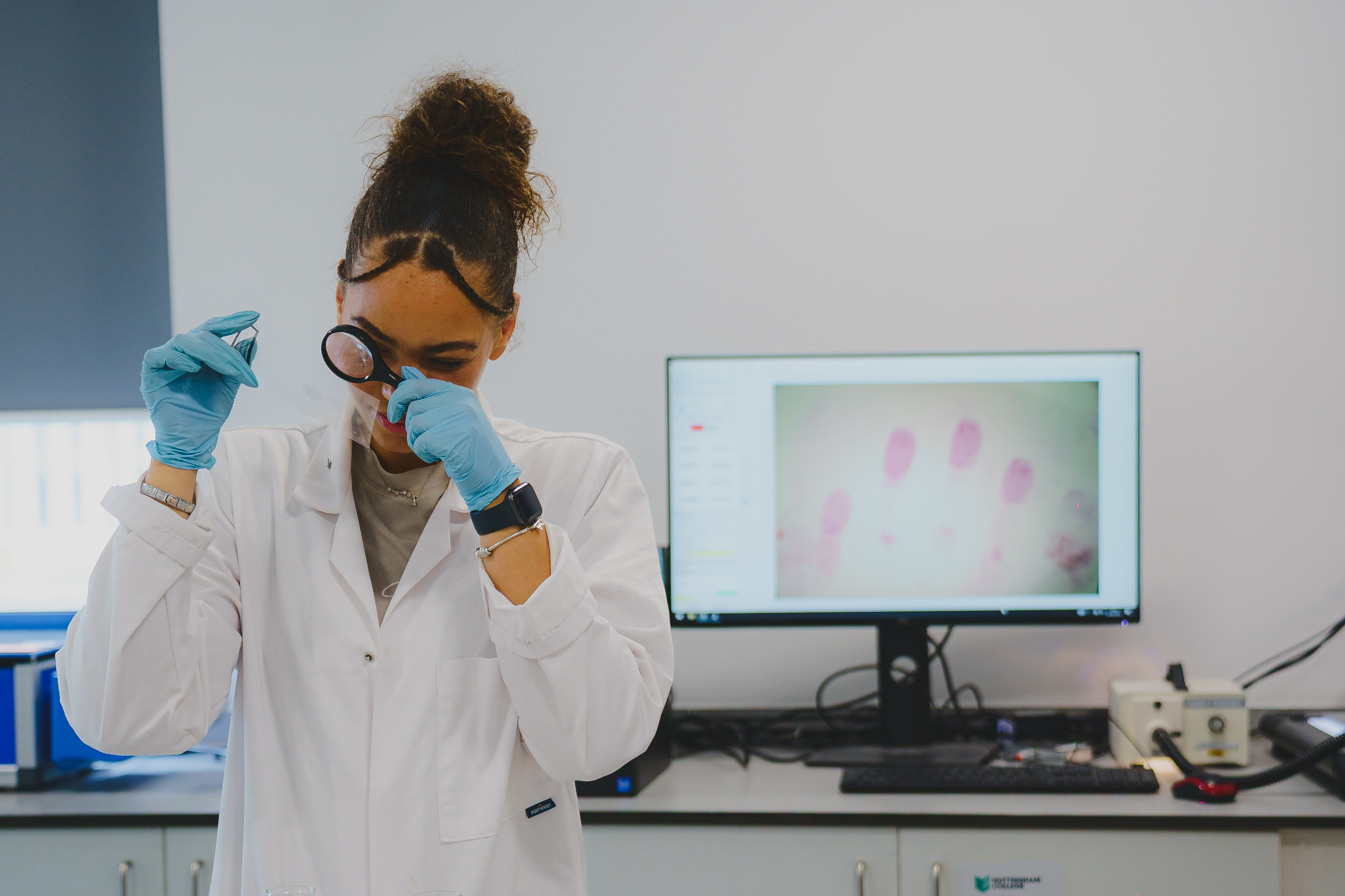 Forensic Science Student, Faith, inspecting finger prints in lab with magnifying glass.