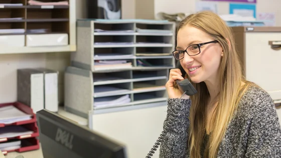 An apprentice answering the telephone in an office.