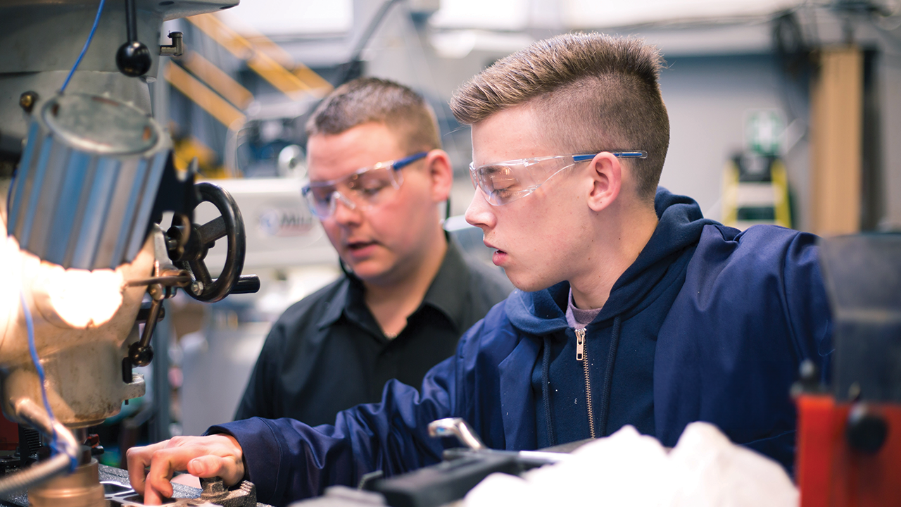 Engineering student being directed how to use a machine