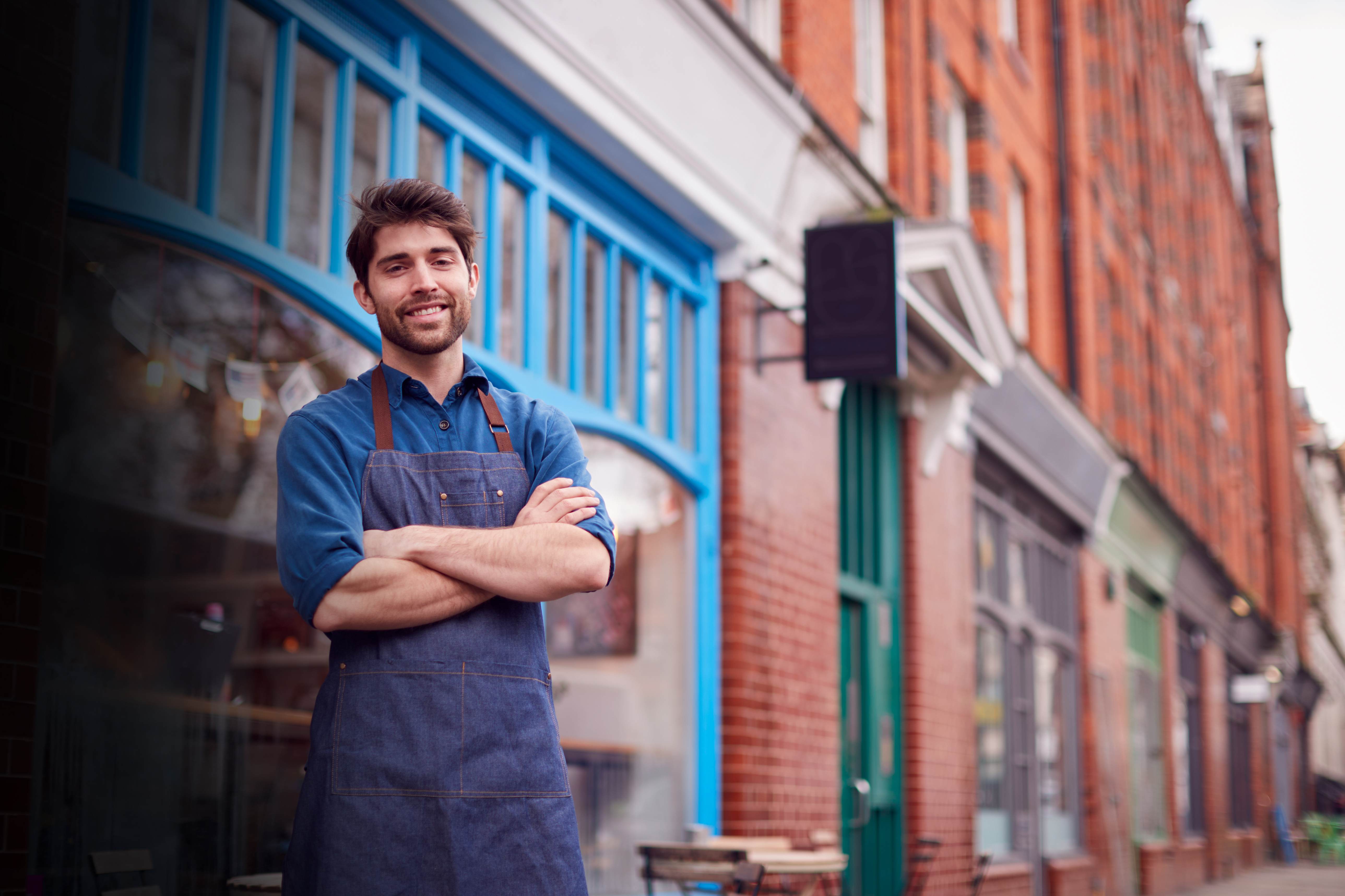 Man in overalls in front of a store.