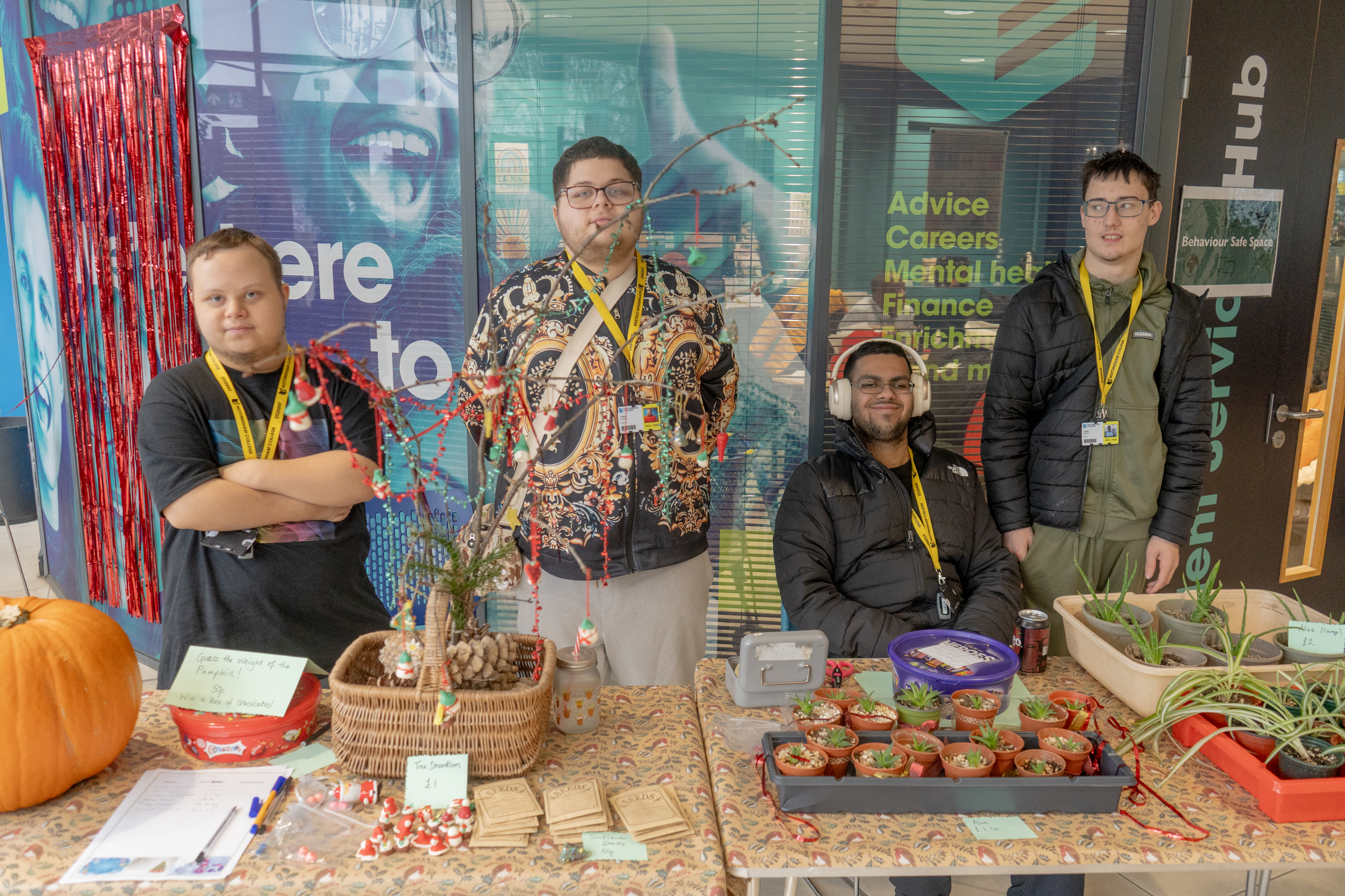 Four students smiling behind their stall, selling hand made Christmas ornaments