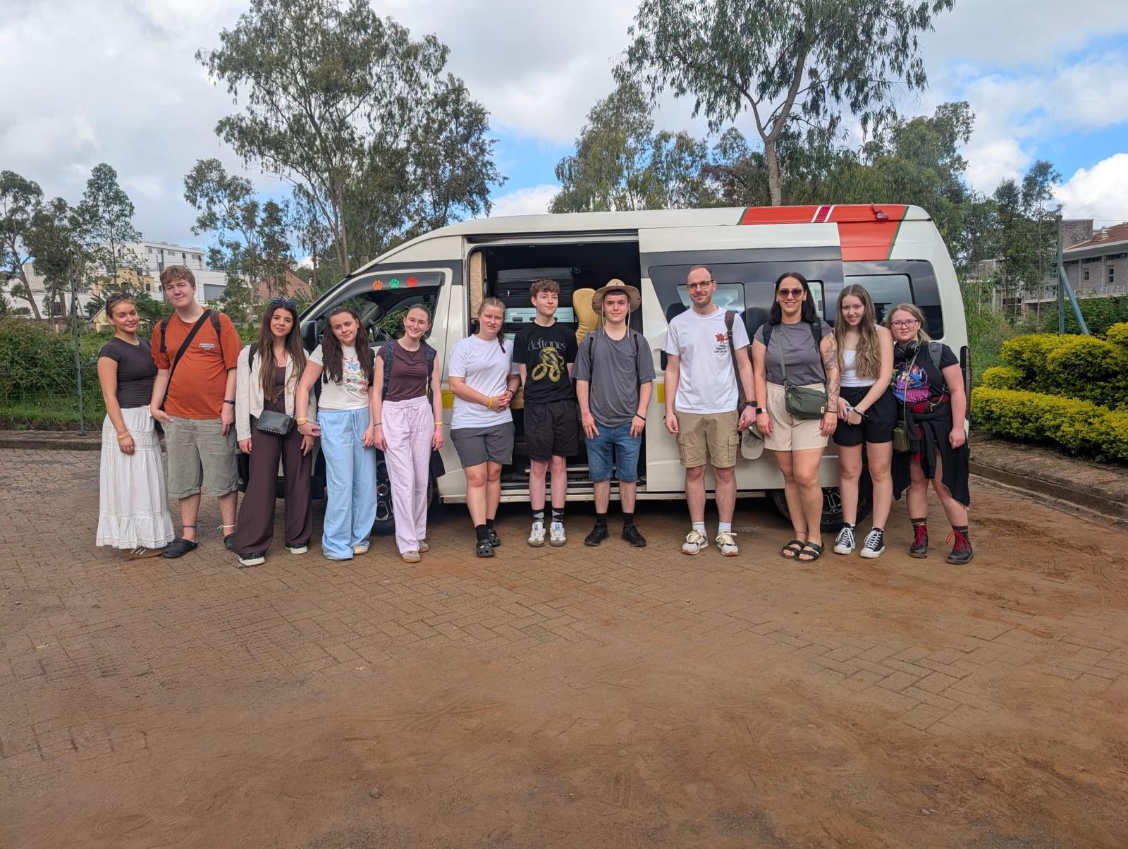A photograph of a group of students in front of a campervan.