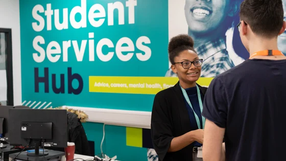Member of staff with a student, smiling at our Student Services Hub