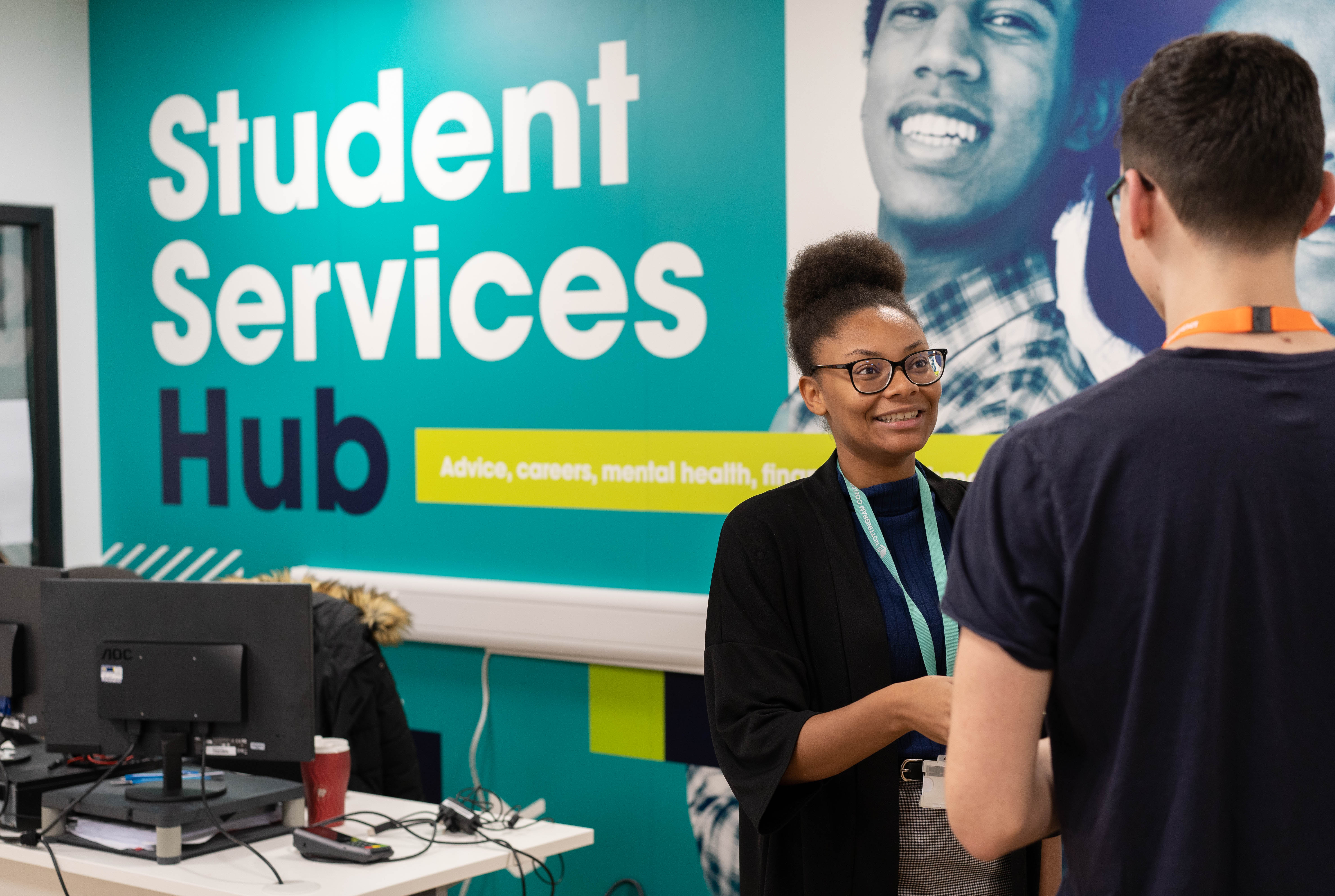 Member of staff with a student, smiling at our Student Services Hub