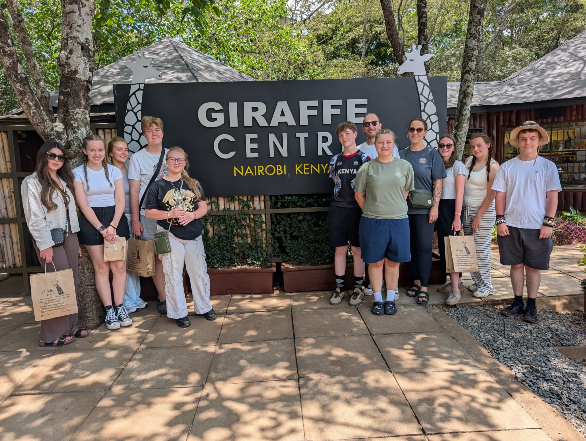 A group of students photographed in front of the sign to the Giraffe Centre.