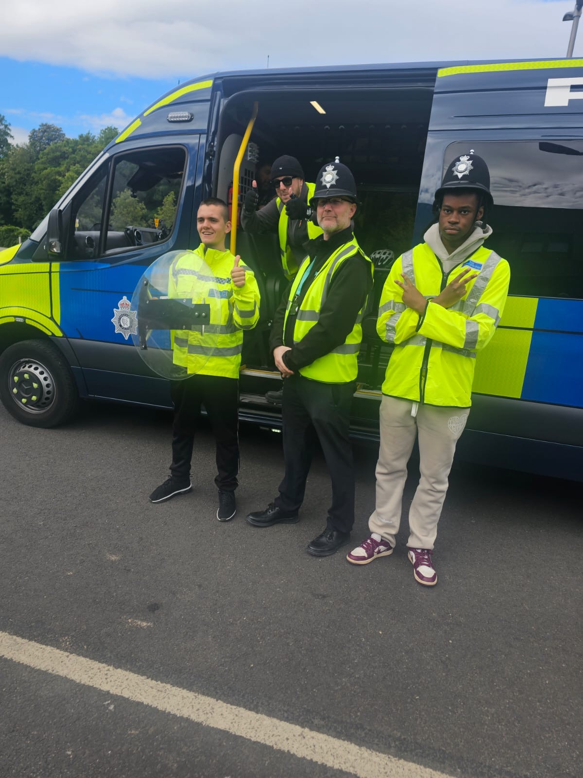 Students pose in front of a police van dressed in the uniform