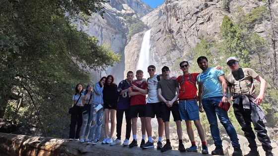 A large group of student stood in front of a waterfall
