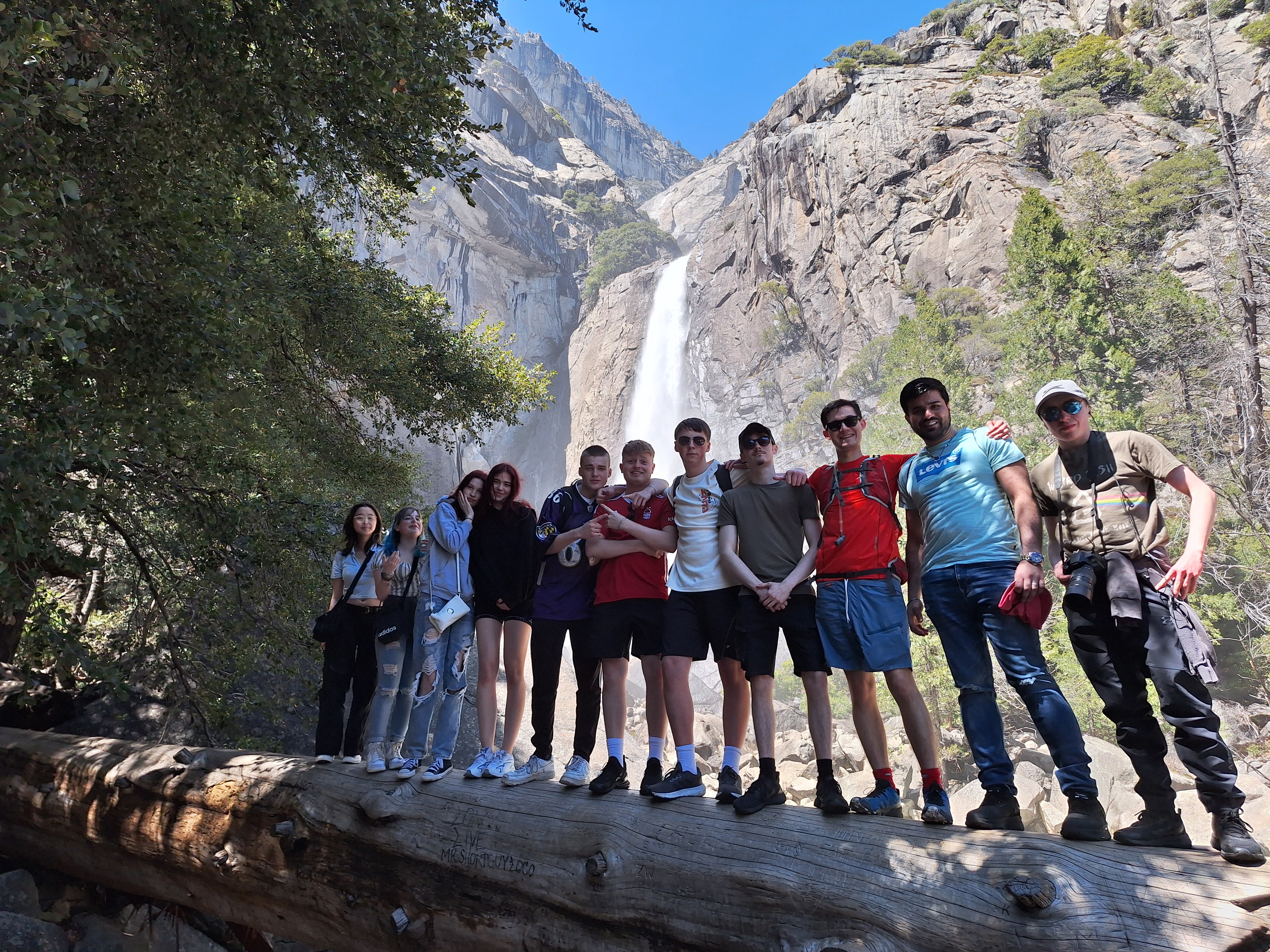 A large group of student stood in front of a waterfall
