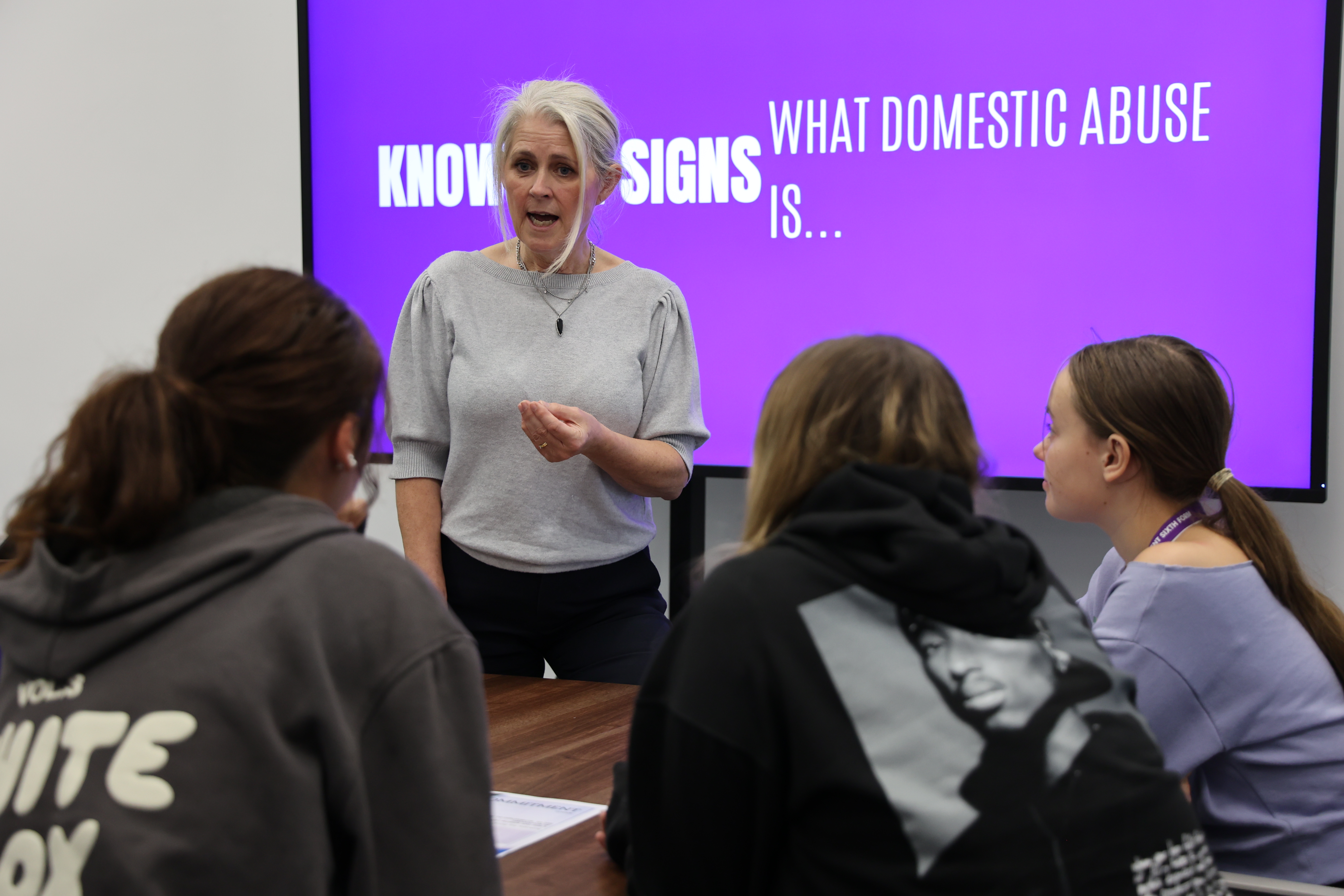 Woman explaining what domestic abuse is infront of a three students