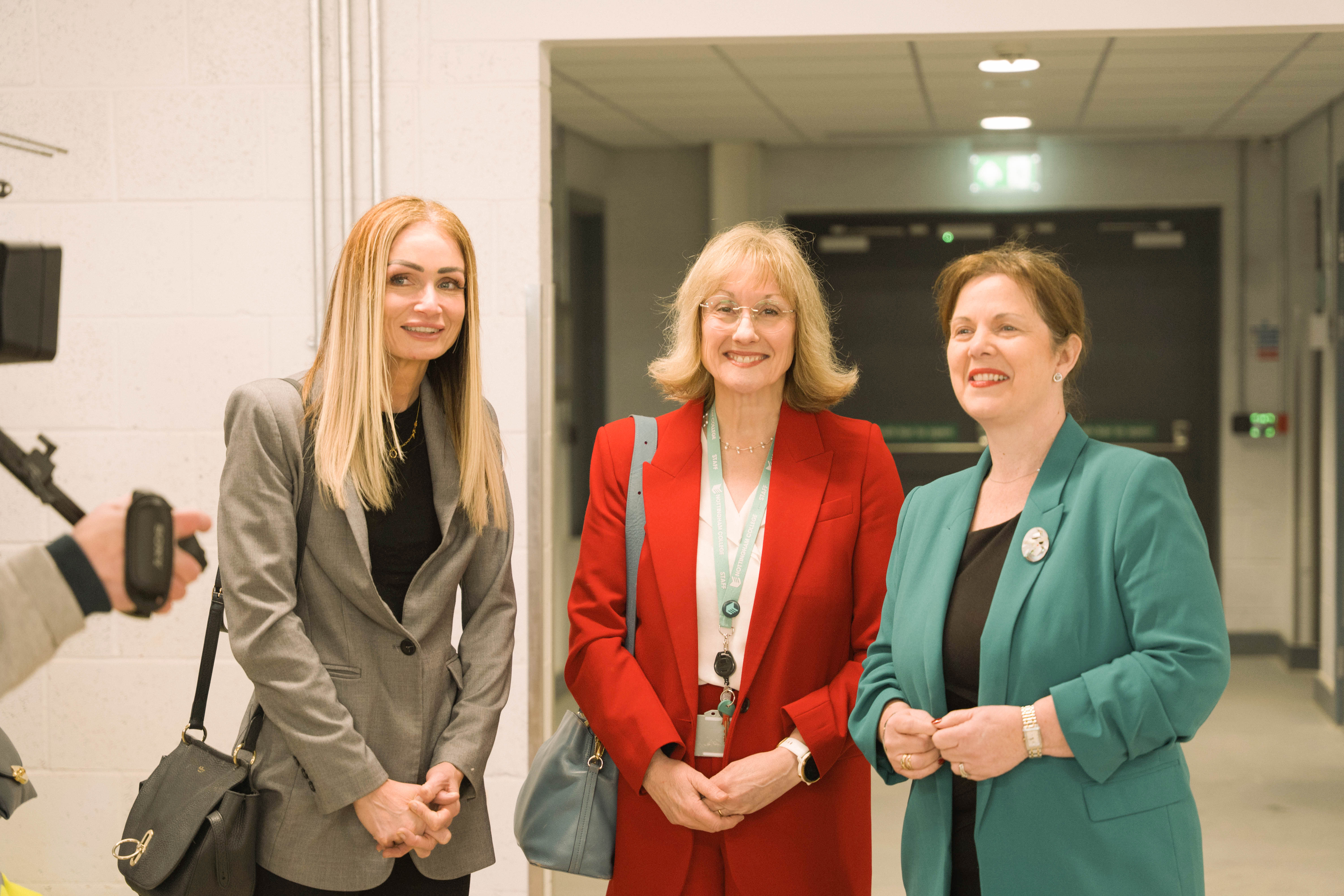 Three women smiling at the camera in the construction skills centre