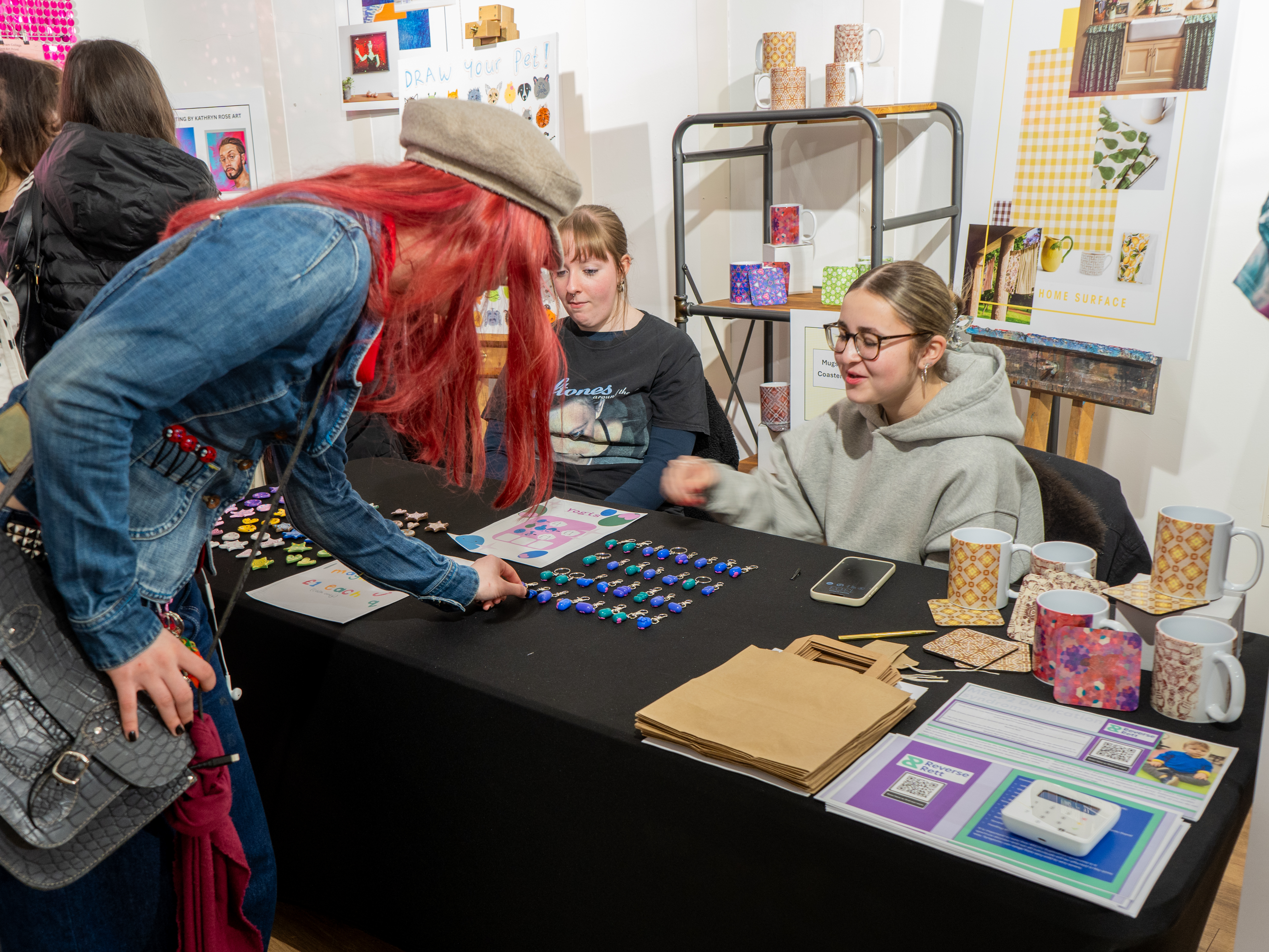 Students speaking to a customer about handmade magnets on sale