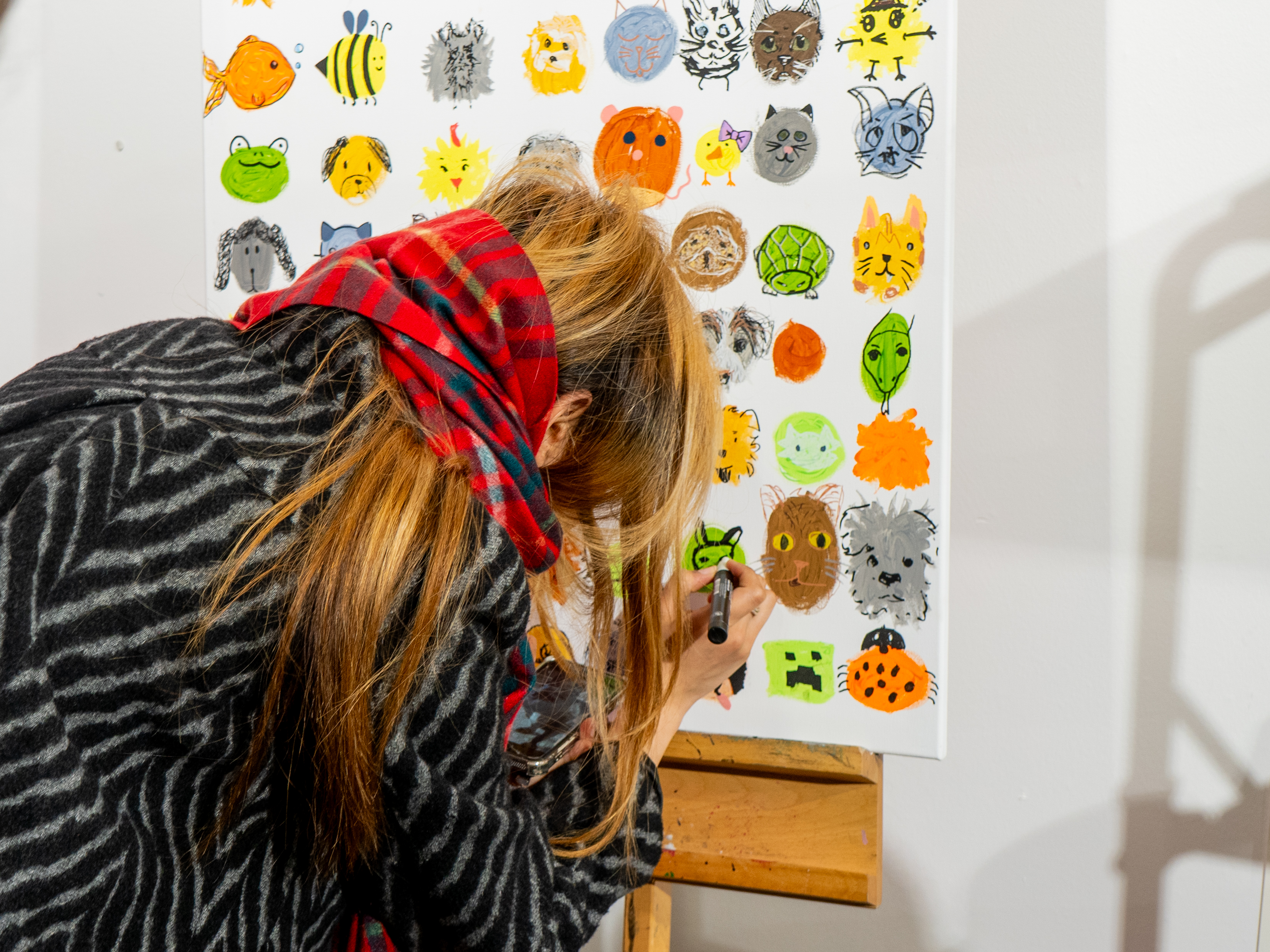 Woman drawing her dog on a colourful board of pets