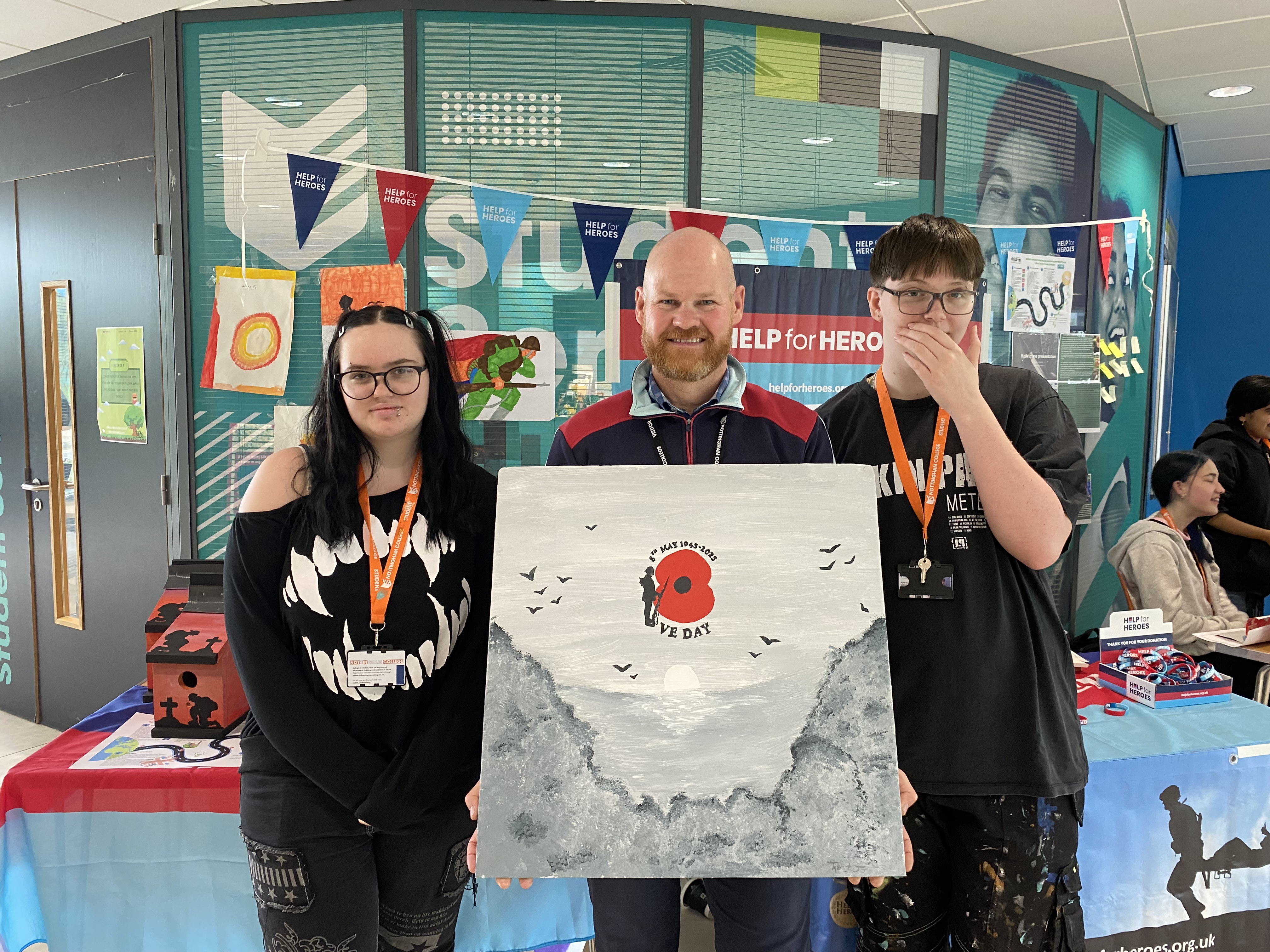 Two students smiling for a picture with Dean Williams holding a memorial piece of art