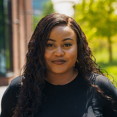 A headshot of Rebekah standing outside the City Hub with trees in the background.