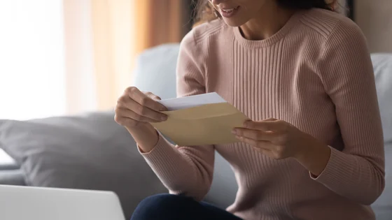 A person opening an envelope containing their exam results