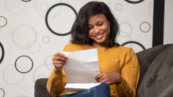 A woman smiling at a paper containing her exam results