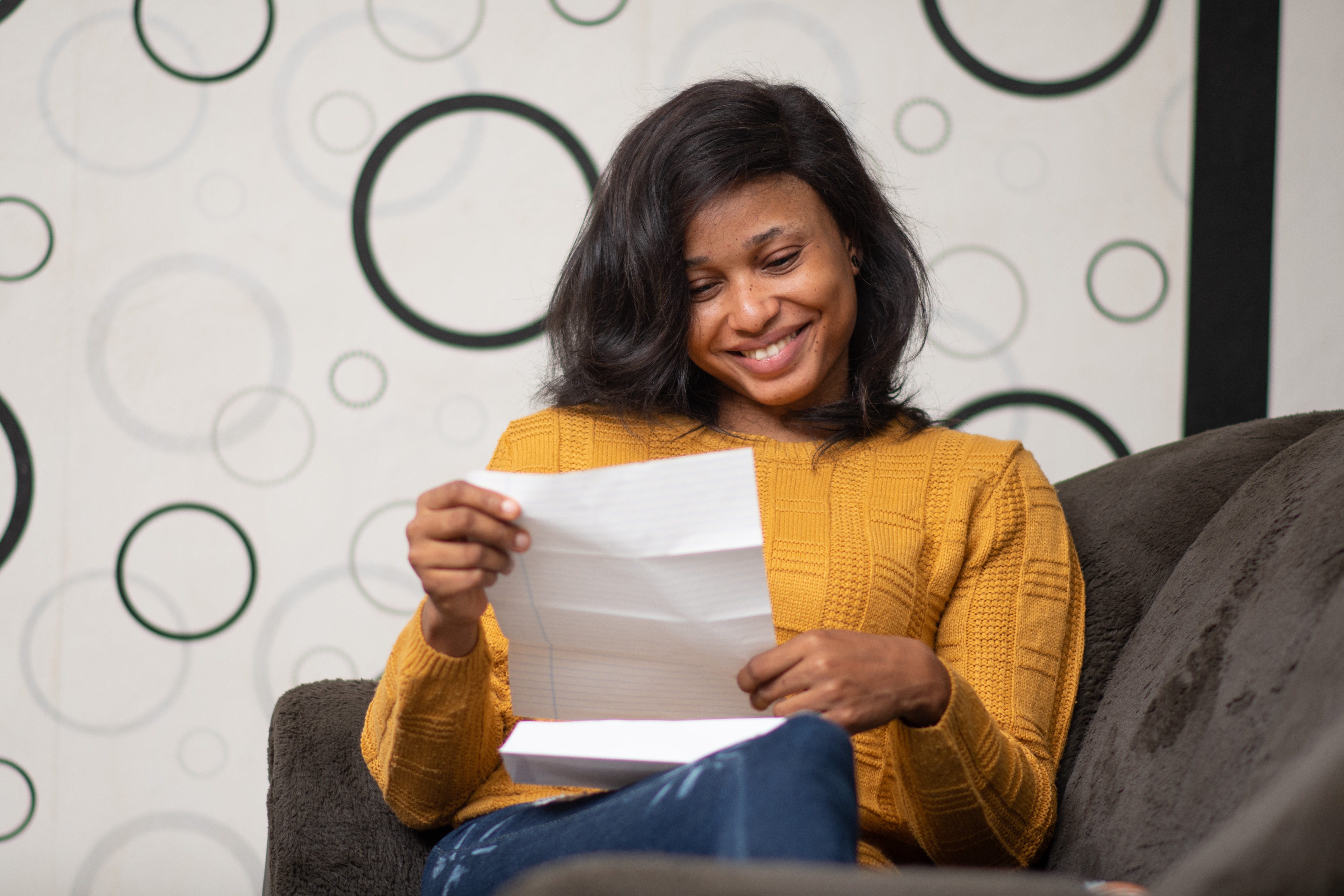 A woman smiling at a paper containing her exam results