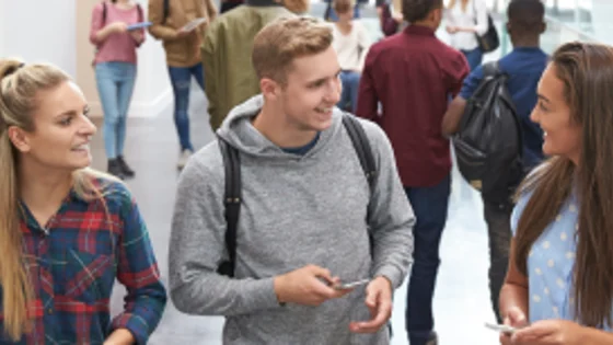 Three students stood in a corridor smiling