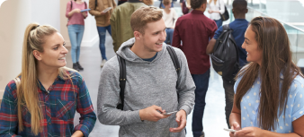 Three students stood in a corridor smiling