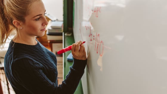A student writing on a whiteboard.