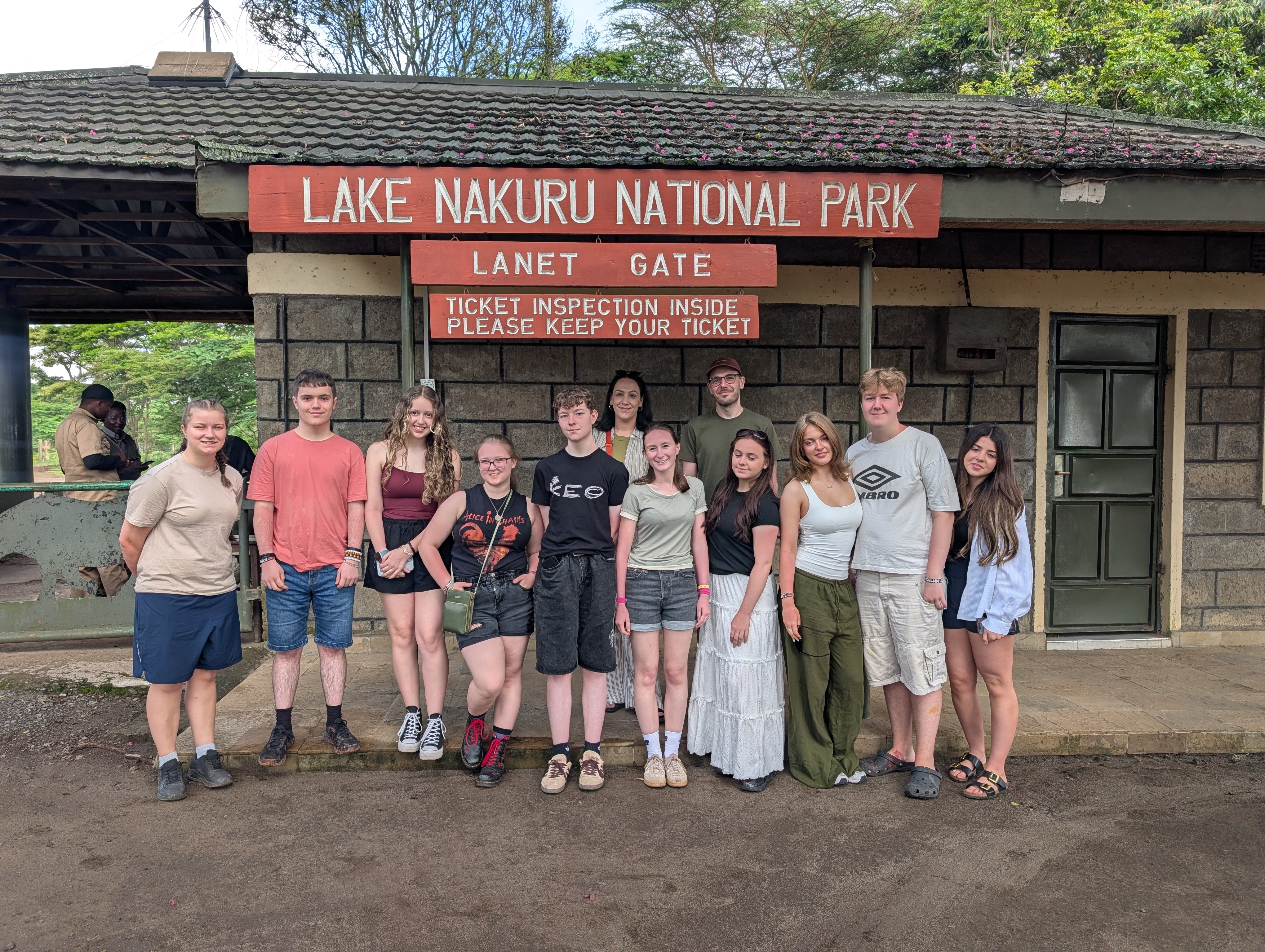 A group of students in front of a large wooden hut with a sign that says 'Lake Nakuru National Park'.
