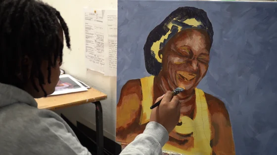 A student painting a portrait picture of a woman smiling